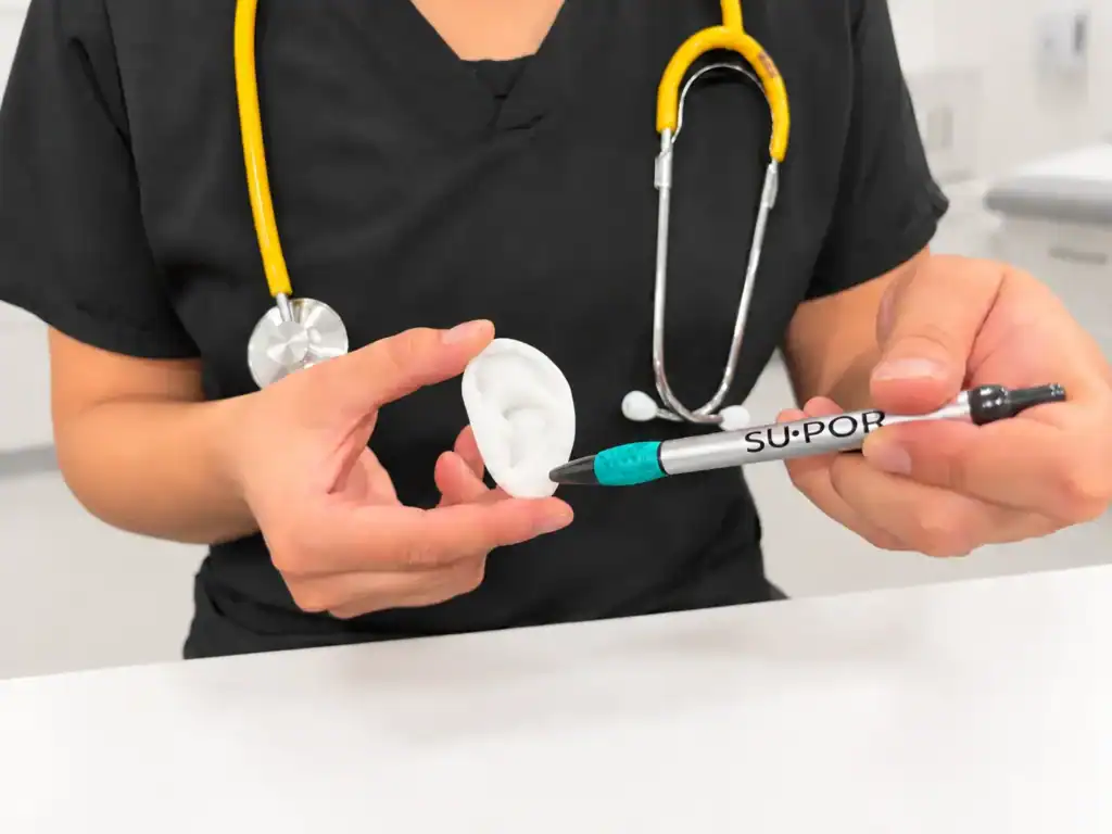 Poriferous SuPor Ear Implant Surgeon Examining Ear Model